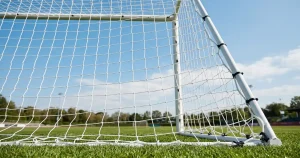 Fußballtor mit Netz und Spielfeld im Hintergrund